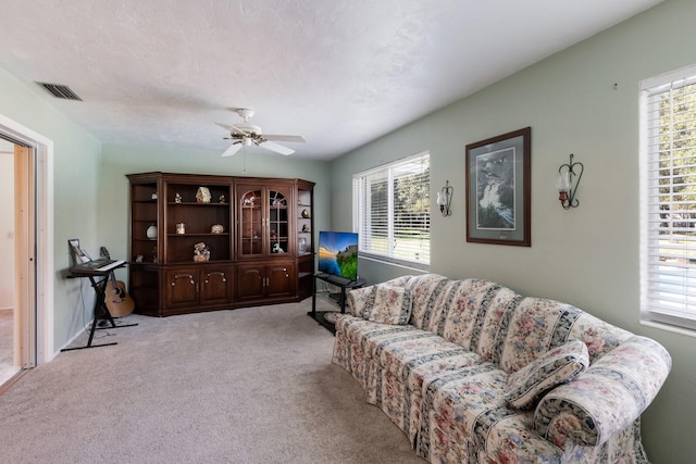 living room with light colored carpet, a wealth of natural light, and ceiling fan