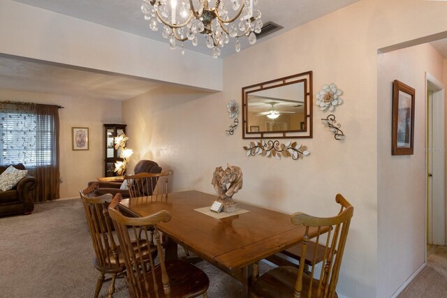 carpeted dining room featuring ceiling fan with notable chandelier