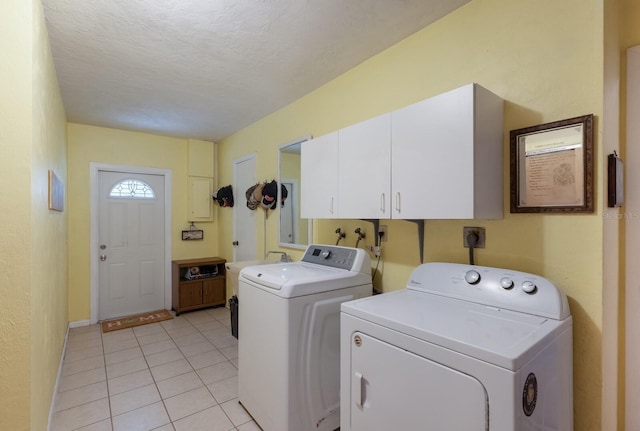 laundry area with light tile patterned flooring, cabinets, a textured ceiling, and washing machine and dryer