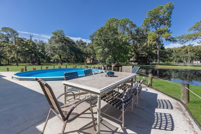 view of pool featuring a lawn, a patio area, and a water view