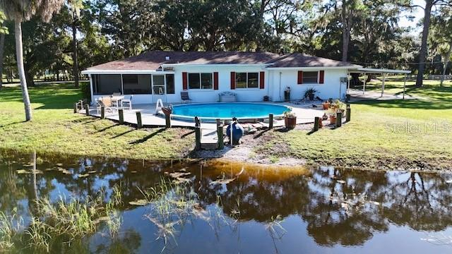 back of property with a yard, a water view, and a sunroom