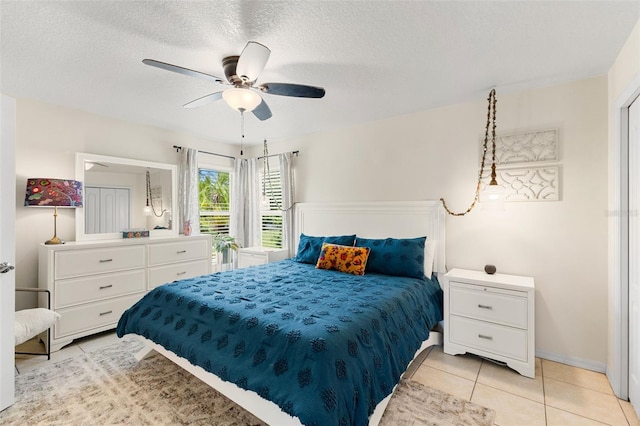 bedroom with ceiling fan, light tile patterned flooring, and a textured ceiling