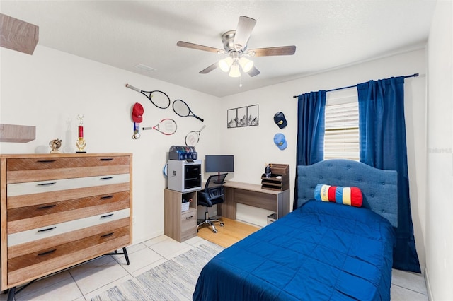 bedroom featuring a textured ceiling, light tile patterned floors, and ceiling fan