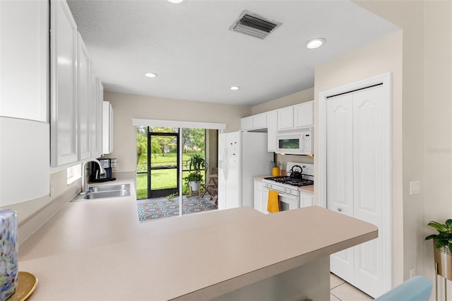 kitchen with white cabinetry, white appliances, light tile patterned floors, kitchen peninsula, and sink