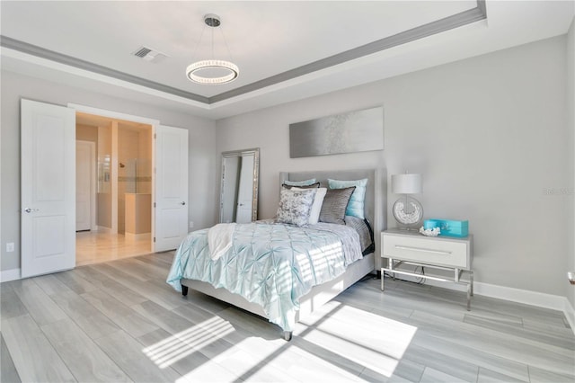 bedroom featuring light wood-type flooring and a raised ceiling