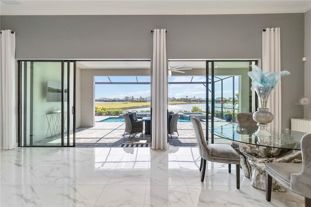 dining space featuring ceiling fan, a water view, and ornamental molding