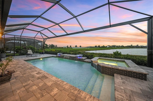 pool at dusk featuring glass enclosure, a water view, pool water feature, an in ground hot tub, and a patio area