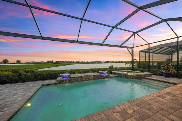 pool at dusk featuring an in ground hot tub, a lanai, pool water feature, a water view, and a patio area