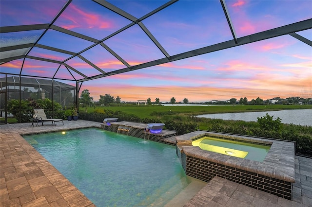 pool at dusk featuring an in ground hot tub, a lanai, pool water feature, a water view, and a patio