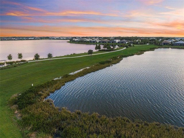 aerial view at dusk featuring a water view