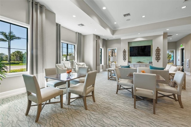 dining space with light carpet and a high ceiling