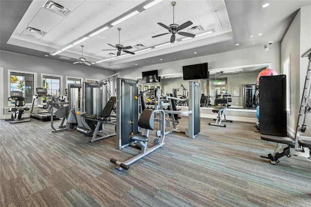 workout area featuring carpet, a raised ceiling, and ceiling fan