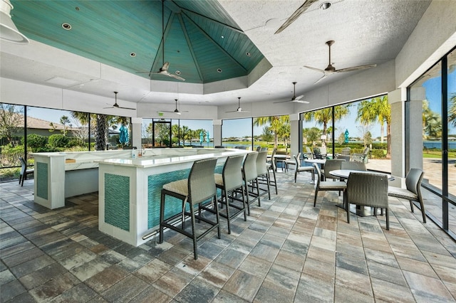 interior space with ceiling fan, a towering ceiling, an island with sink, and a healthy amount of sunlight