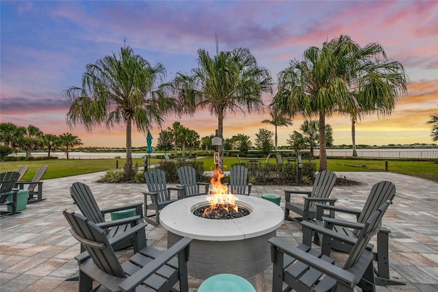 patio terrace at dusk featuring a yard and a fire pit