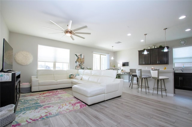 living room featuring plenty of natural light, ceiling fan, and light hardwood / wood-style flooring