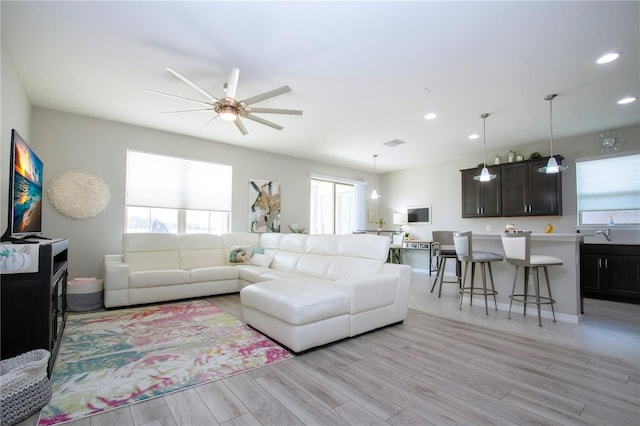 living room featuring plenty of natural light, ceiling fan, and light wood-type flooring