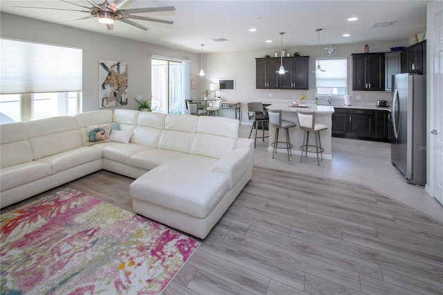 living room featuring ceiling fan, light hardwood / wood-style floors, and a healthy amount of sunlight