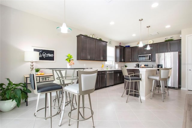 kitchen with hanging light fixtures, a breakfast bar area, appliances with stainless steel finishes, and dark brown cabinets