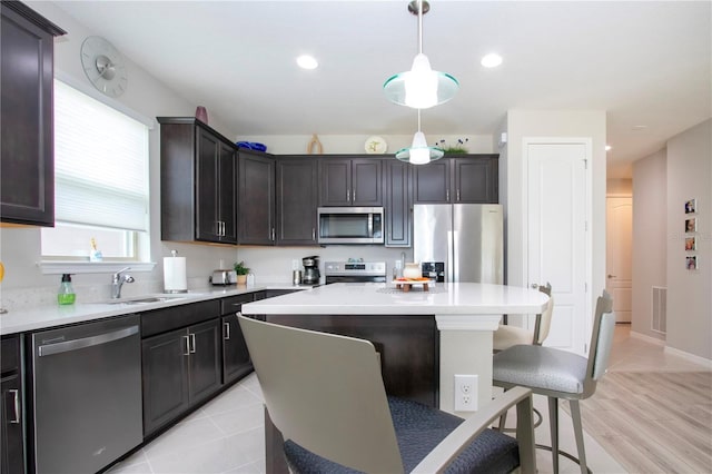 kitchen with a center island, light hardwood / wood-style flooring, stainless steel appliances, sink, and a breakfast bar area