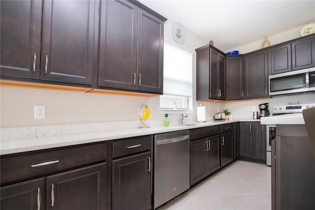 kitchen with stainless steel appliances, sink, dark brown cabinetry, and light tile patterned flooring