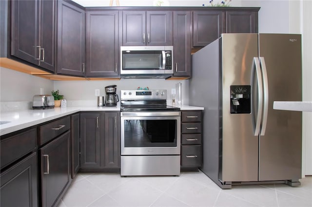 kitchen with light stone counters, stainless steel appliances, dark brown cabinetry, and light tile patterned flooring