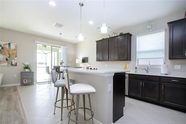 kitchen featuring hanging light fixtures, a kitchen island, sink, a breakfast bar, and light hardwood / wood-style floors