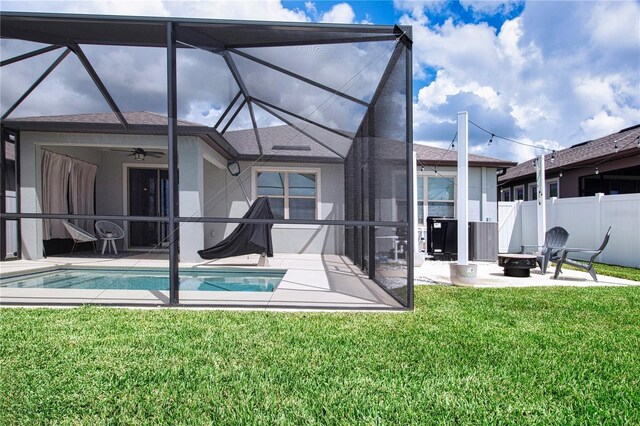 rear view of house featuring a lanai, a lawn, an outdoor fire pit, ceiling fan, and a patio