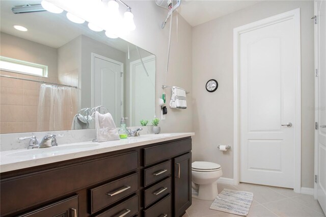 bathroom with tile patterned flooring, vanity, toilet, and walk in shower