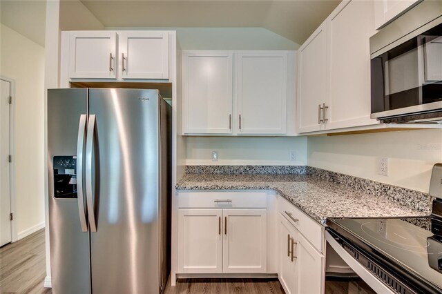 kitchen featuring stainless steel appliances, light stone countertops, and white cabinets