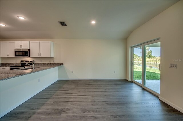 kitchen with visible vents, dark stone counters, dark wood finished floors, appliances with stainless steel finishes, and white cabinetry