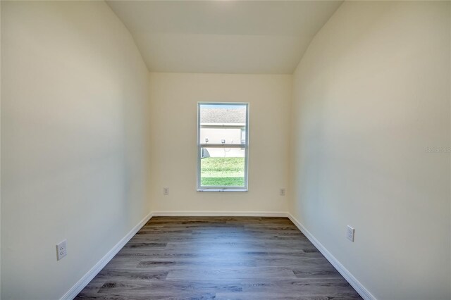 unfurnished room with lofted ceiling, dark wood-style floors, and baseboards