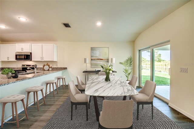 dining room featuring vaulted ceiling, dark wood finished floors, visible vents, and recessed lighting