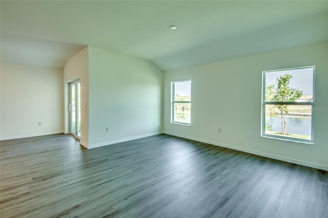 empty room featuring lofted ceiling, dark wood finished floors, and baseboards