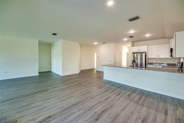 kitchen featuring visible vents, appliances with stainless steel finishes, open floor plan, and dark stone counters