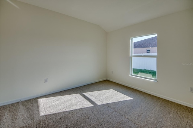 carpeted spare room with lofted ceiling and baseboards