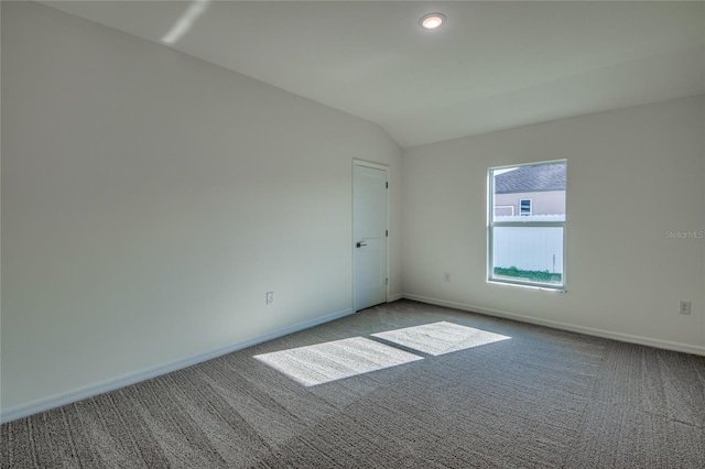 empty room with vaulted ceiling, carpet flooring, and baseboards