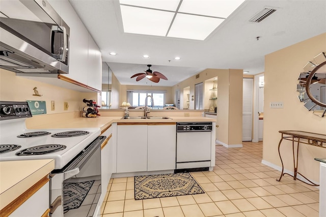 kitchen featuring white appliances, white cabinetry, kitchen peninsula, and sink