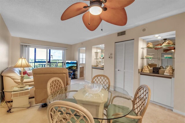 dining area featuring a textured ceiling, light colored carpet, and ceiling fan