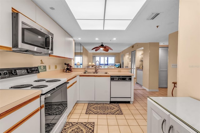 kitchen featuring white cabinets, white appliances, kitchen peninsula, and sink