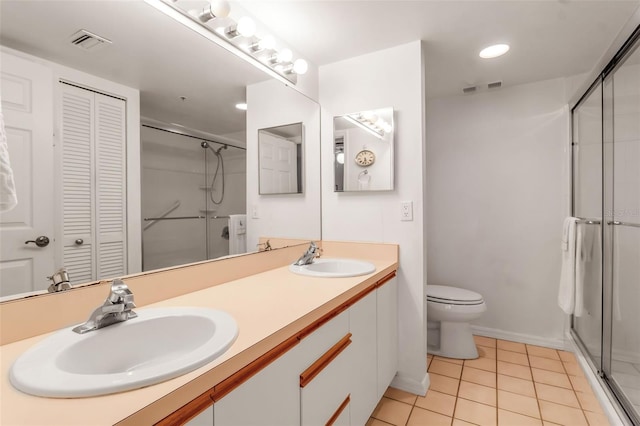 bathroom featuring a shower with door, vanity, toilet, and tile patterned flooring