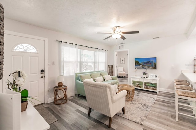 living room with light hardwood / wood-style flooring, ceiling fan, and a healthy amount of sunlight