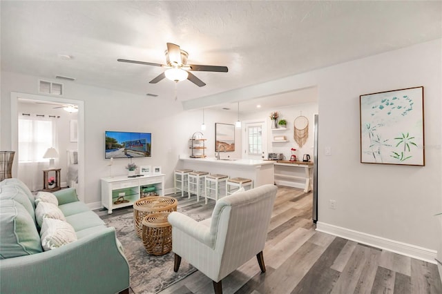 living room featuring light wood-type flooring, sink, and ceiling fan