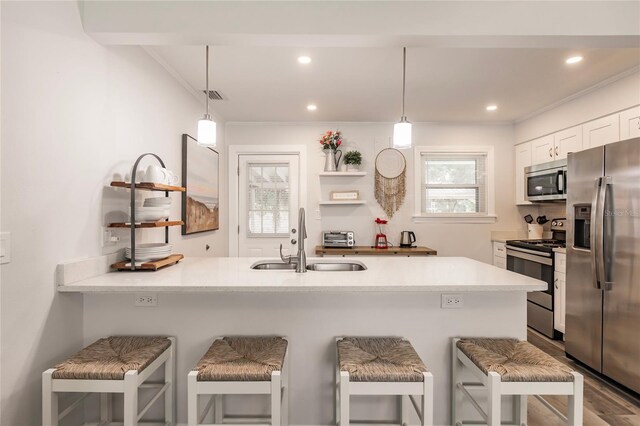 kitchen featuring appliances with stainless steel finishes, kitchen peninsula, sink, and a kitchen breakfast bar