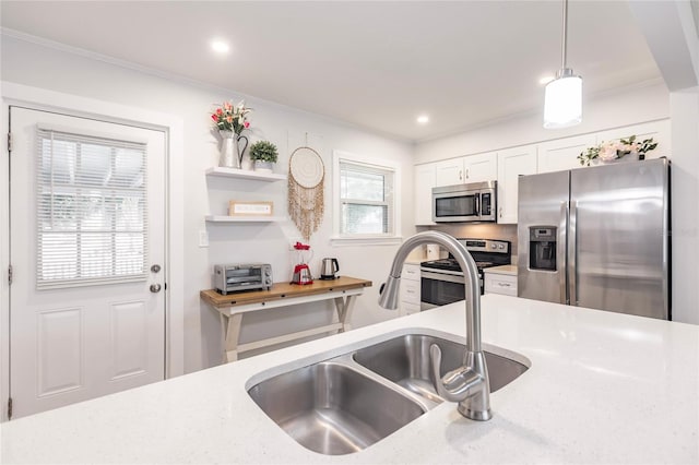 kitchen with white cabinets, light stone countertops, stainless steel appliances, sink, and pendant lighting