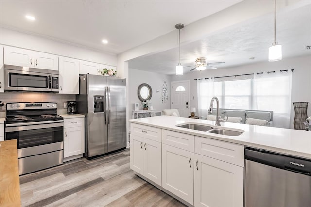 kitchen with pendant lighting, stainless steel appliances, sink, white cabinetry, and ceiling fan