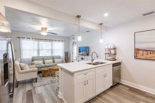 kitchen with appliances with stainless steel finishes, light hardwood / wood-style floors, hanging light fixtures, sink, and white cabinetry