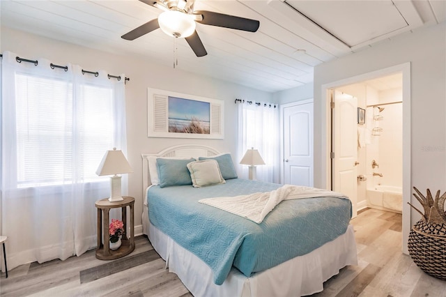 bedroom with ensuite bathroom, multiple windows, and light hardwood / wood-style floors