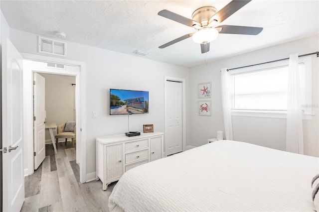 bedroom with a textured ceiling, ceiling fan, a closet, and light hardwood / wood-style floors