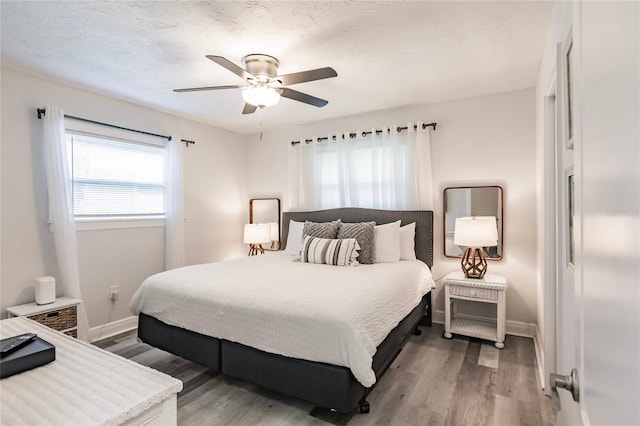 bedroom with hardwood / wood-style floors, ceiling fan, and a textured ceiling