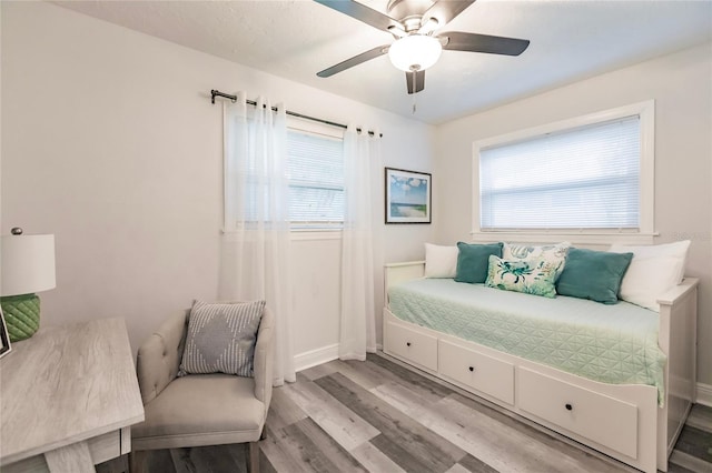 bedroom featuring ceiling fan, light wood-type flooring, and multiple windows